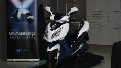 הקטנוע החדש באירוע ההשקה, קטנוע חשמלי בצבע לבן עם באנר של החברה מאחור