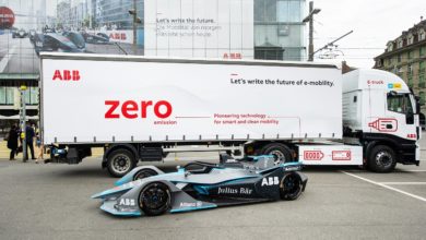 משאית חשמלית בצבע לבן של ABB עם רכב מירוץ לפניה