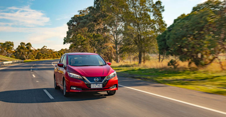 ניסאן ליף החדשה בצבע אדום על כביש פתוח עם עצים מאחור