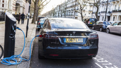 טסלה מודל S שחורה ברחובות לונדות מחוברת לעמד טעינה