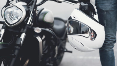 אדם מחזיק קסדה לידע אופנוע חשמלי בצבע שחור