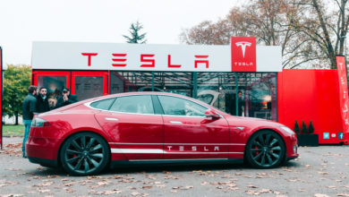 טסלה מודל S אדומה חונה ממול לאולם תצוגה של החברה
