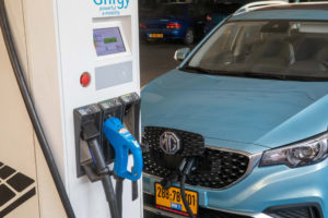 MG חשמלית בצבע תכלת מחוברת לעמדת טעינה מהירה של ג׳ינרג׳י ב-M הדרך