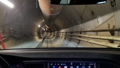 רכב טסלה מפנים נוסע בתוך מנהרה אפורה של Boring
