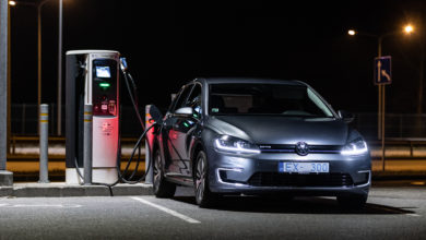 פולקסווגן גולף חשמלית בצבע אפור כהה חונה בחניה ומחוברת לעמדת טעינה בלילה