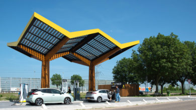 תחנת טעינה עם סככים סולאריים בצבע צהוב עם רכבים חשמליים נטענים