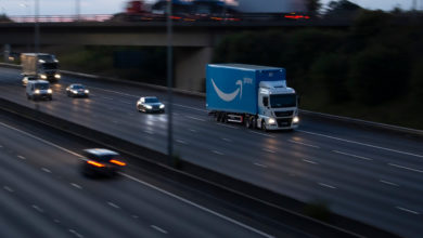 משאית של אמזון פריים בצבע כחול על כביש מהיר בבריטניה