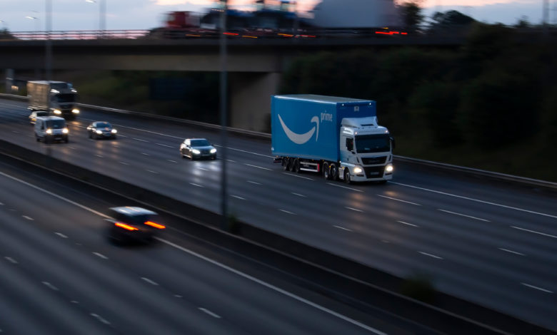 משאית של אמזון פריים בצבע כחול על כביש מהיר בבריטניה