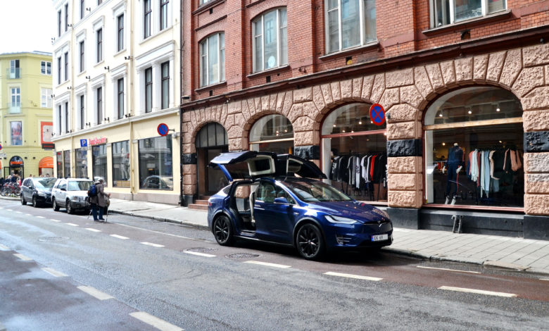 טסלה מודל X כחולה עם דלתות אחוריות פתוחות ברחוב בעיר אוסלו נורווגיה