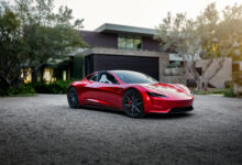 טסלה רודסטר בצבע אדום בחניה של בית