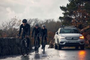 וולוו XC40 חשמלית בכביש ביער לצד שלושה רוכבי אופניים