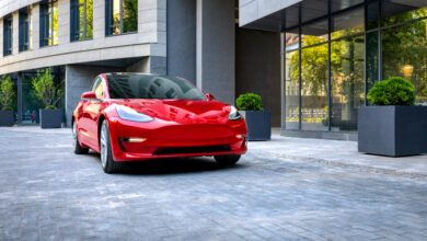 טסלה מודל 3 אדומה בנסיעה באיזור עירוני