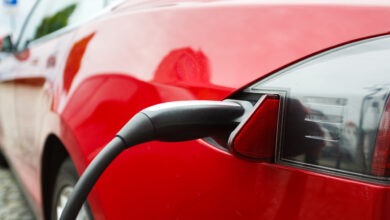 מבט על שקע הטעינה של טסלה בצבע אדום המחוברת לעמדת טעינה ברחוב