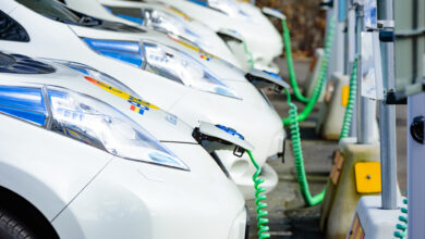 צי של רכבי ניסאן ליף מחובר לעמדות טעינה עם כבל ירוק מסולסל