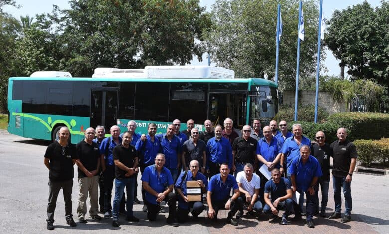 נציגי החברות גולדן דרגון ישראל ואגד בהדרכה במפעל הייצור, עם אוטובוס חשמלי של אגד מאחוריהם