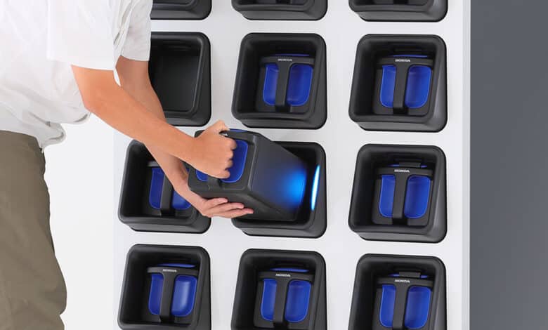 כוורת להחלפת סוללות לקטנועים חשמליים של חברת הונדה, עם אדם שמוציא את אחת מהסוללות לצורך החלפה