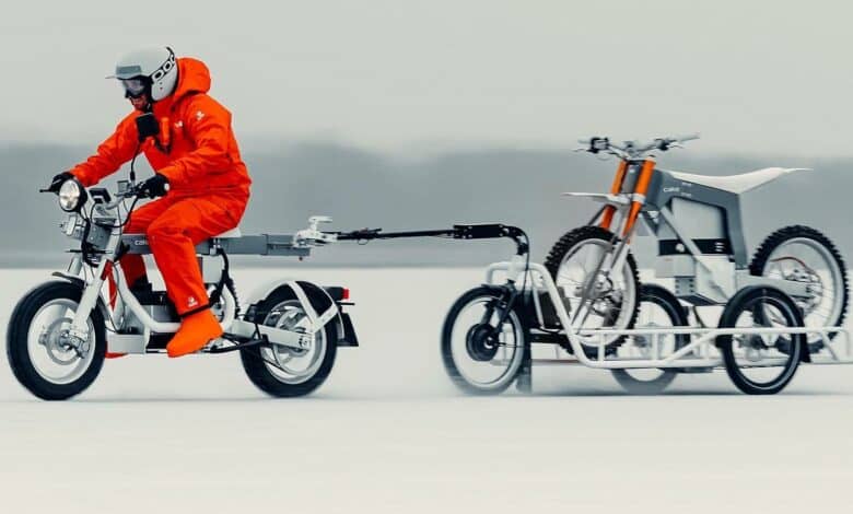 רוכב על אופנוע של CAKE בשלג גורר עגלה שעליה אופנוע נוסף של CAKE