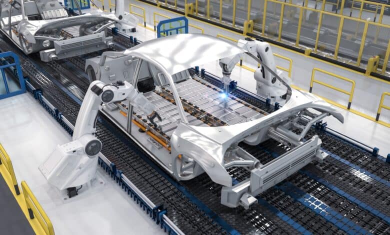 הדמיה של זרוע רובוטית שמלחימה תאי סוללה על שלדה של רכב חשמלי בפס ייצור במפעל לרכבים חשמליים