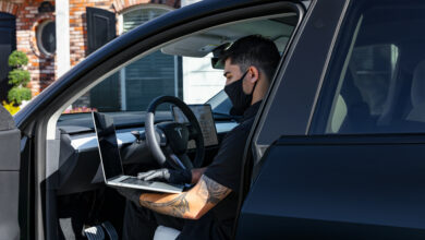 עובד של טסלה עם מחשב מטפל ברכב טסלה