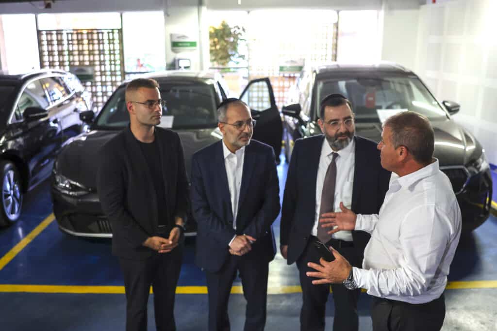 חברי הכנסת מקבלים הסבר על הרכבים החשמליים, כאשר הרכבים החשמליים עומדים מאחוריהם בחניה