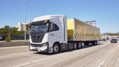 סמי טריילר מבית ניקולה מוטורס עם נגרר צהוב ועליו הכיתוב Anheuser-Busch בנסיעה בכביש מהיר בארצות הברית