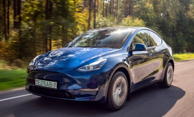 טסלה מודל Y כחולה בנסיעה בכביש בינעירוני ביום שמשי