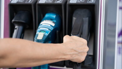 יד של אישה מחזיקה מחבר מסוג CCS2 של טעינה מהירה בעמדת טעינה של רכב חשמלי עם שלושה מחברים