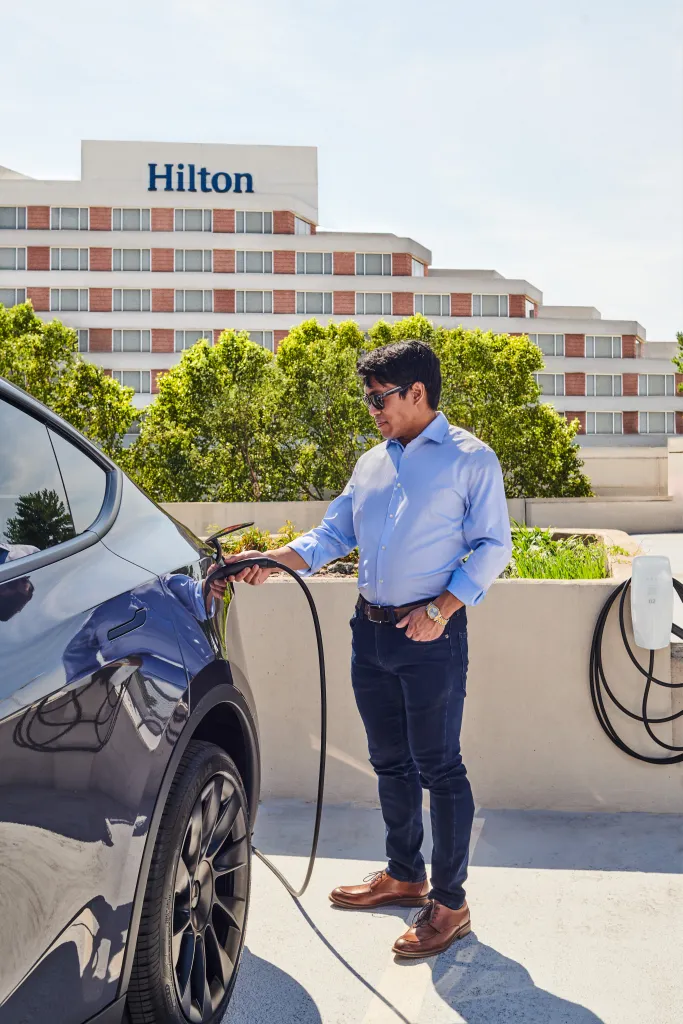 אדם מחבר רכב של טסלה לעמדת טעינה במלון הילטון
