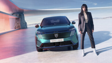 אישה עומדת לצד פיג׳ו E-3008 החשמלית החדשה