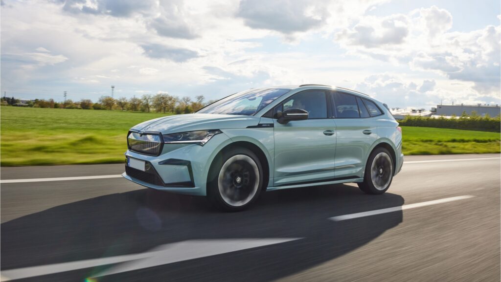 סקודה אניאק בצבע תכלת בהיר בנסיעה על כביש בינעירוני עם שדות מוריקים מאחור