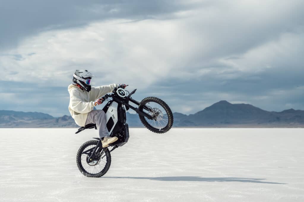 רוכב אופנוע מרים גלגל עם ניו XQi3 חשמלי בשטח מושלג