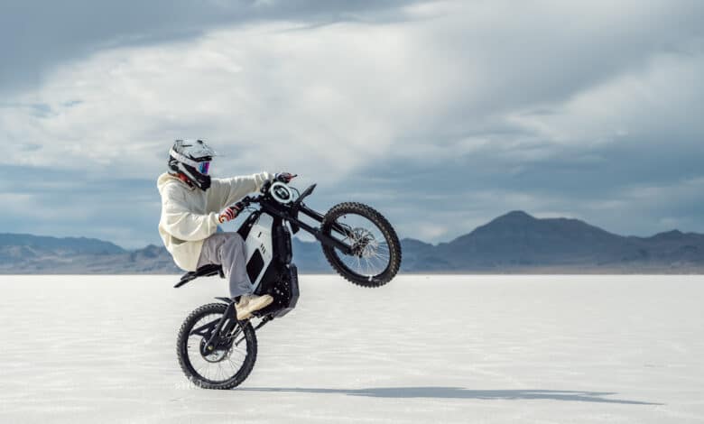 רוכב אופנוע מרים גלגל עם ניו XQi3 חשמלי בשטח מושלג