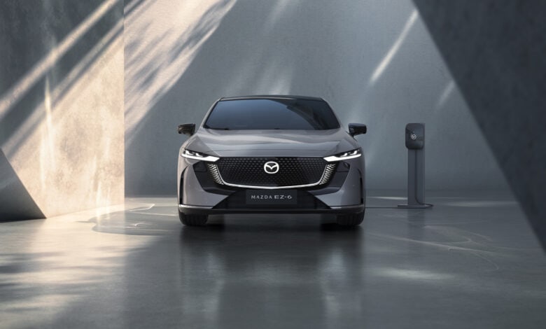 מבט קדמי על מאזדה EZ-6 מחוברת לעמדת טעינה לרכב חשמלי