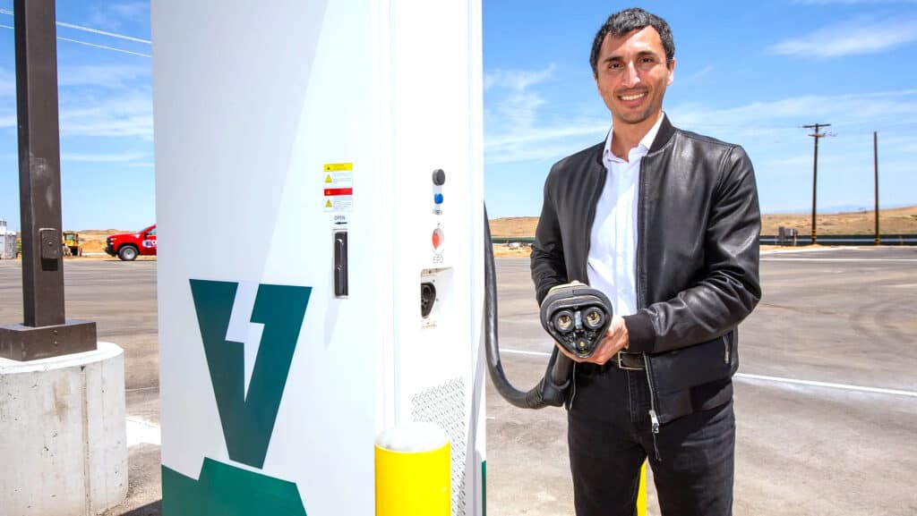 מנכ״ל WattEV מחזיק את מחבר הטעינה MCS ליד תחנת הטעינה של החברה