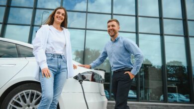 גבר ואישה עומדים לצד רכב חשמלי בזמן טעינה של הרכב