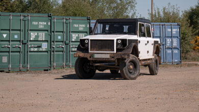 תמונת חזית של רכב שטח חשמלי של מונרו, רכב קופסתי בעל קווים חדים הדומים לדיפנדר, חונה בשטח