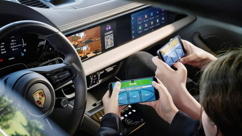 משחק בסמארטפון בתוך תא הנוסעים של פורשה מקאן עם מסכי המולטימדיה של הרכב מציגים את המשחק