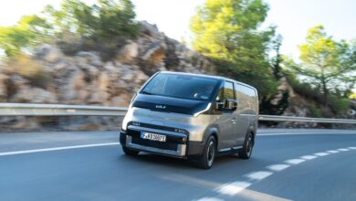 קיה PV5 רכב מסחרי חשמלי בגרסת מטען בצבע אפור פלדה בנסיעה על כביש בינעירוני