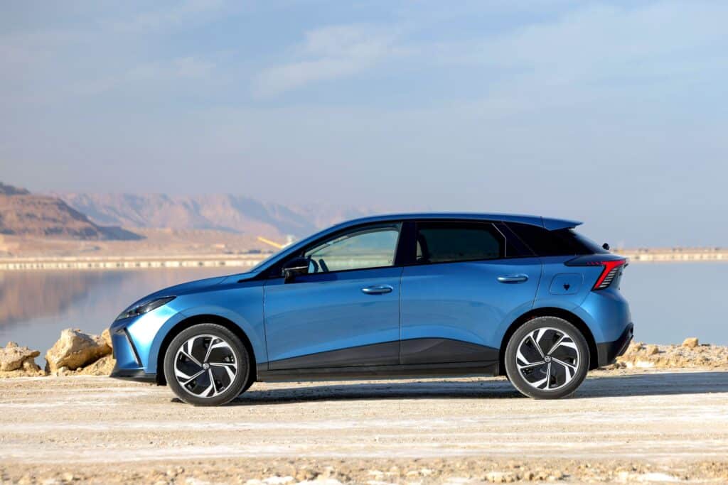 רכב חשמלי בצבע כחול על רקע נוף מדברי וים, דגם חדש של EV Magazine לרכב חשמלי.